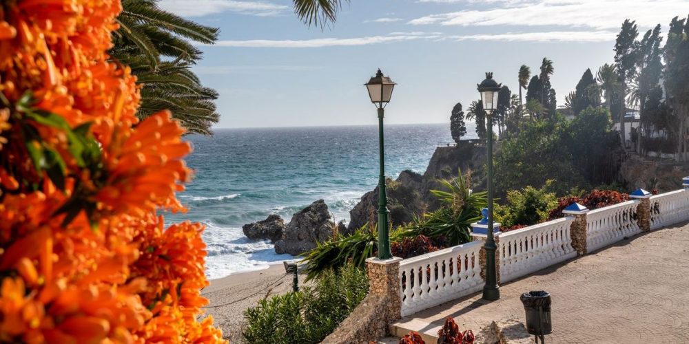 "Mirador del Bendito" and Carabeillo Beach in Nerja - Malaga - Spain. Beautiful landscape in south of Spain, famous travel destination. Orange trumpet flowers. Sunny winter day